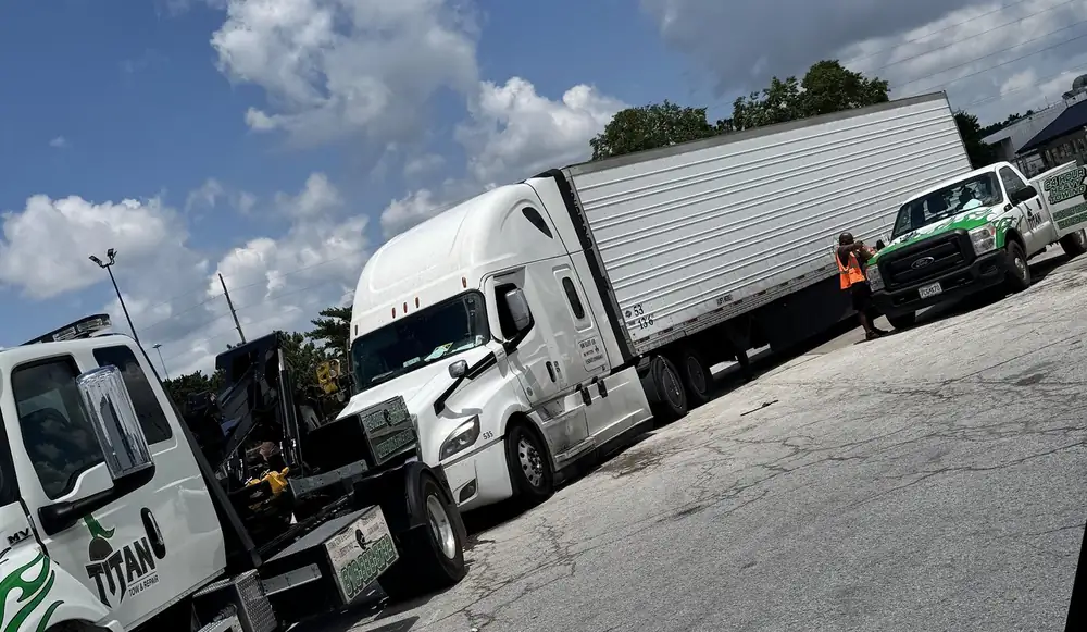 Titan wrecker, a semi tractor with a dry van trailer, and a Titan service truck staged in the yard.